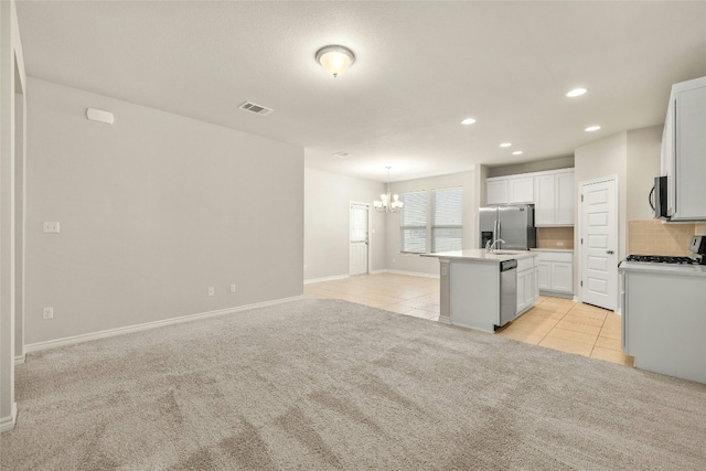 kitchen featuring light carpet, an island with sink, tasteful backsplash, white cabinetry, and stainless steel appliances