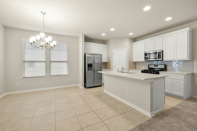 kitchen with backsplash, sink, light tile patterned floors, an island with sink, and stainless steel appliances