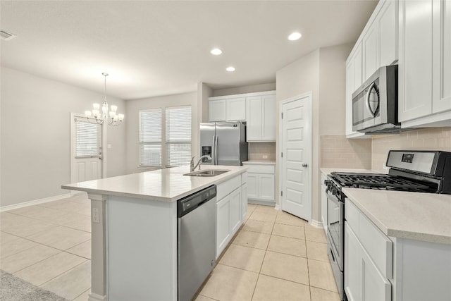 kitchen with backsplash, white cabinets, a center island with sink, appliances with stainless steel finishes, and decorative light fixtures