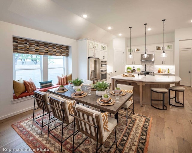 dining room featuring light wood-type flooring and vaulted ceiling