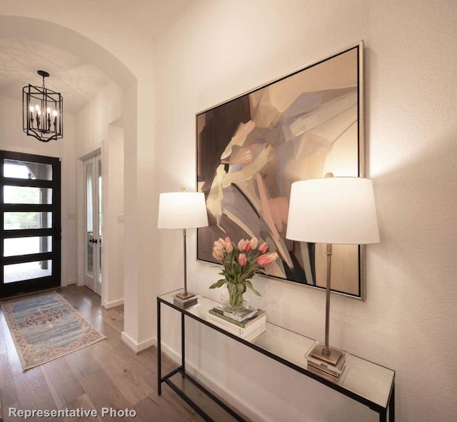 foyer featuring french doors, hardwood / wood-style flooring, and a notable chandelier