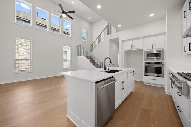 kitchen featuring appliances with stainless steel finishes, a sink, light wood-style flooring, a ceiling fan, and recessed lighting