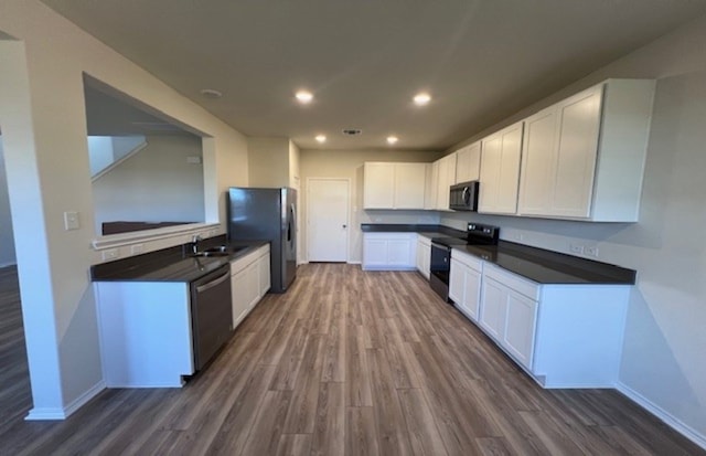 kitchen with sink, white cabinetry, dark wood-type flooring, and black appliances