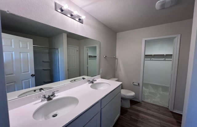 bathroom featuring walk in shower, a textured ceiling, vanity, hardwood / wood-style flooring, and toilet