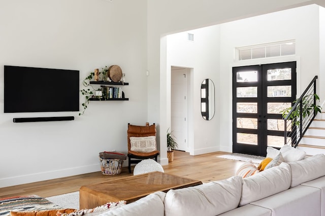 living room with french doors, light hardwood / wood-style flooring, and a high ceiling