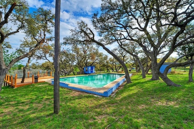 view of pool featuring a lawn and a storage unit