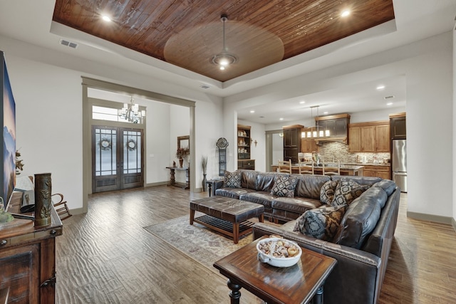 living room with wooden ceiling, dark wood-type flooring, french doors, ceiling fan with notable chandelier, and a raised ceiling