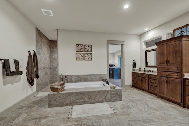 bathroom featuring tiled tub and vanity