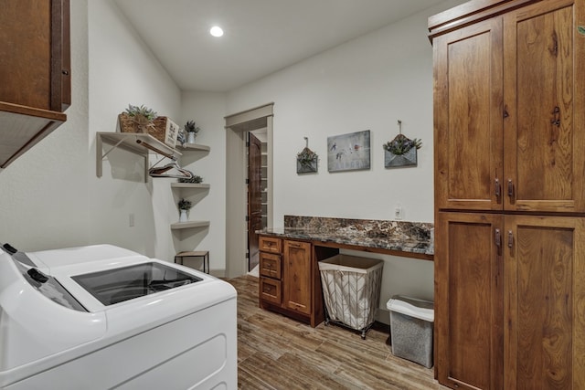 clothes washing area featuring separate washer and dryer, light hardwood / wood-style flooring, and cabinets