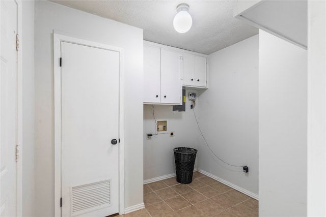 laundry room featuring light tile patterned flooring, cabinets, a textured ceiling, and hookup for a washing machine