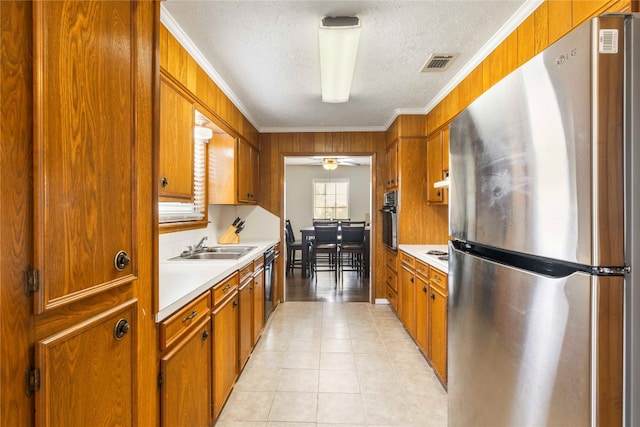 kitchen with ceiling fan, sink, crown molding, light tile patterned floors, and appliances with stainless steel finishes