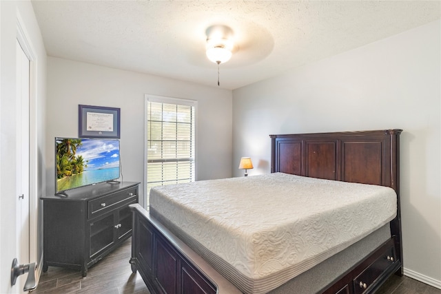 bedroom with a textured ceiling, dark hardwood / wood-style flooring, and ceiling fan