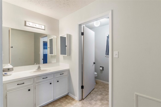 bathroom featuring vanity, a textured ceiling, and toilet