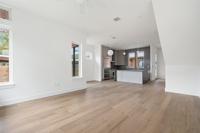 unfurnished living room featuring ceiling fan and light hardwood / wood-style floors