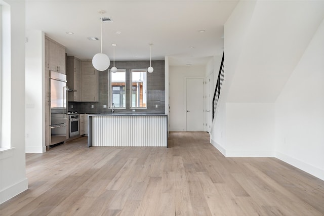 kitchen with decorative light fixtures, light wood-type flooring, backsplash, and appliances with stainless steel finishes