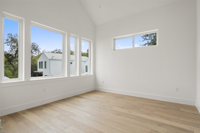 spare room with plenty of natural light, light wood-type flooring, and vaulted ceiling