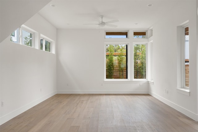 spare room featuring ceiling fan, a wealth of natural light, and light hardwood / wood-style flooring