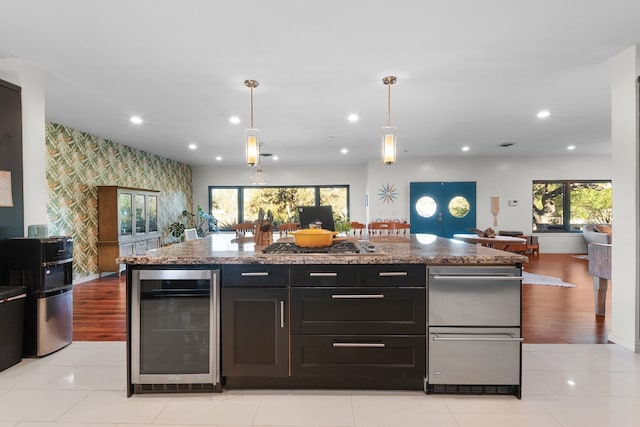 kitchen featuring light stone countertops, pendant lighting, beverage cooler, and light wood-type flooring