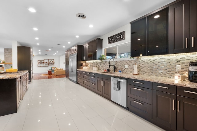 kitchen featuring light stone countertops, sink, tasteful backsplash, stainless steel dishwasher, and light tile patterned flooring