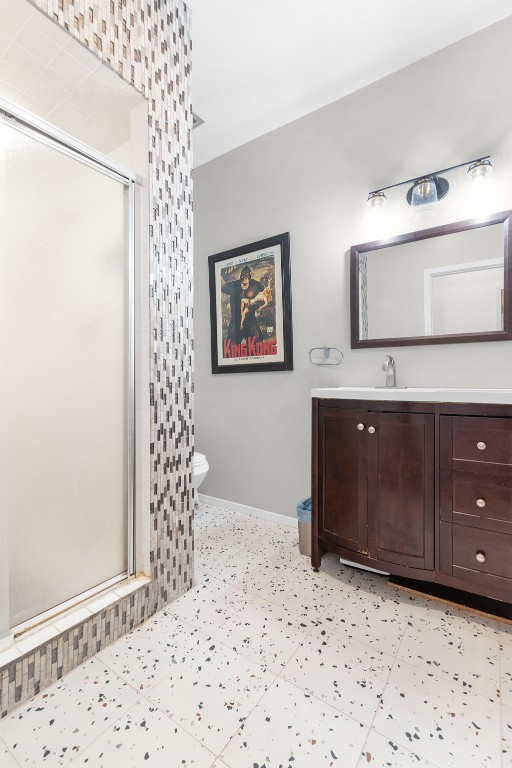 bathroom featuring vanity, toilet, and a shower with shower door