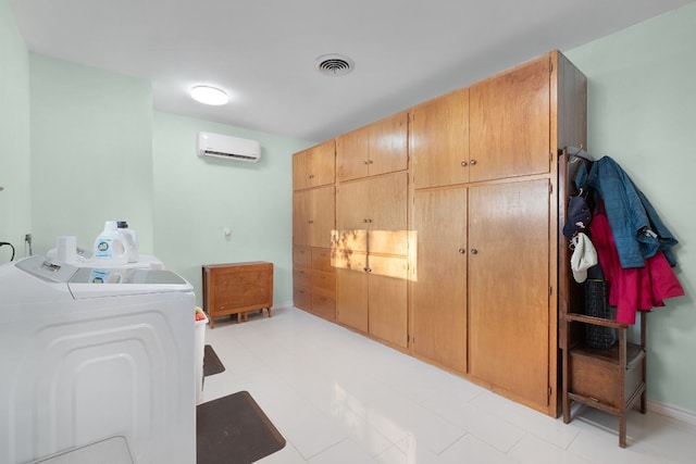 washroom with a wall unit AC, washer and clothes dryer, and cabinets