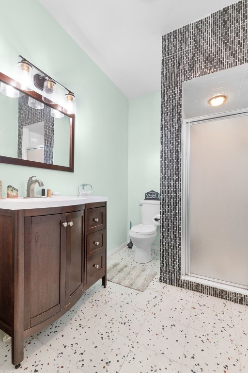 bathroom with vanity, toilet, and a shower with shower door