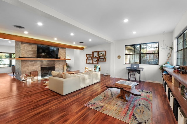 living room with a stone fireplace and dark hardwood / wood-style flooring