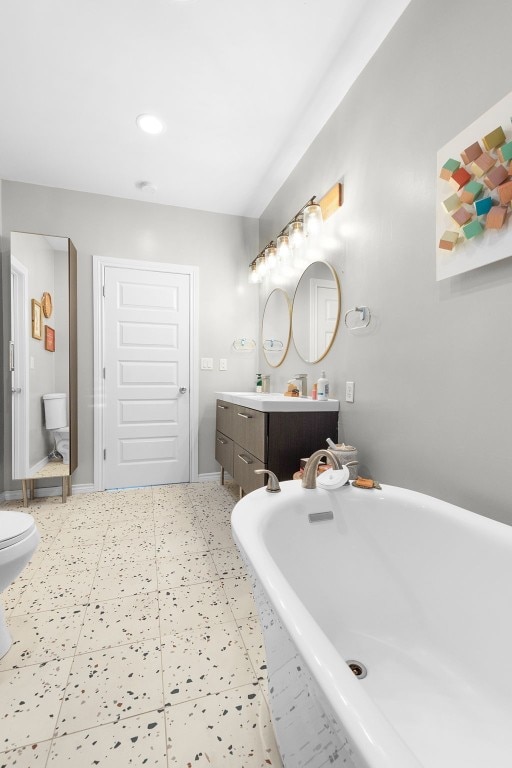 bathroom with vanity, toilet, and tiled tub