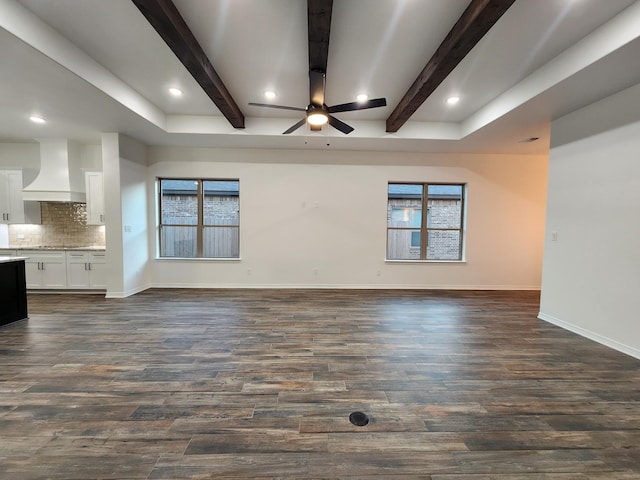 unfurnished living room with plenty of natural light, dark hardwood / wood-style floors, ceiling fan, and beam ceiling