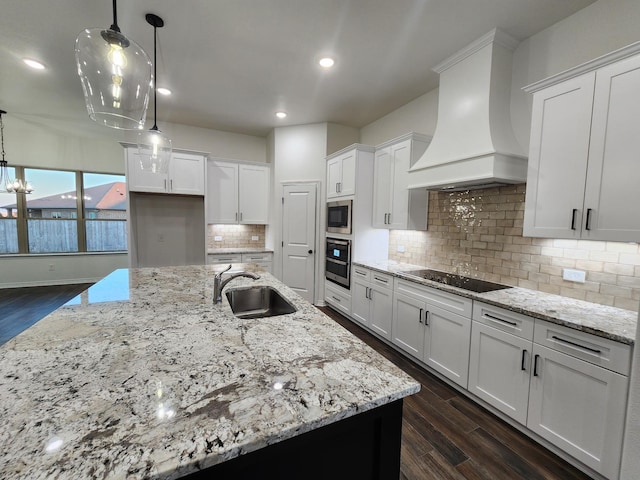 kitchen with sink, premium range hood, white cabinetry, and hanging light fixtures