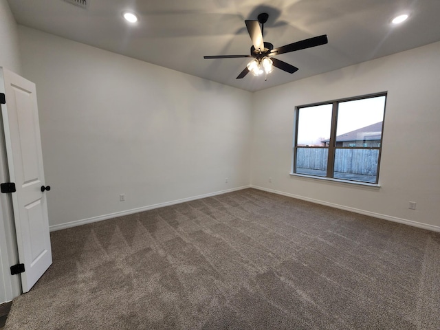 empty room with ceiling fan and dark carpet