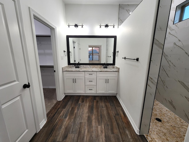 bathroom with hardwood / wood-style flooring, tiled shower, and vanity