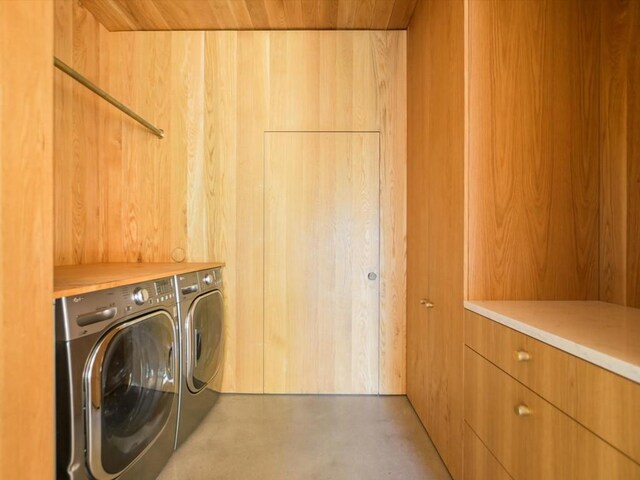 clothes washing area with washing machine and clothes dryer, wooden walls, and wood ceiling