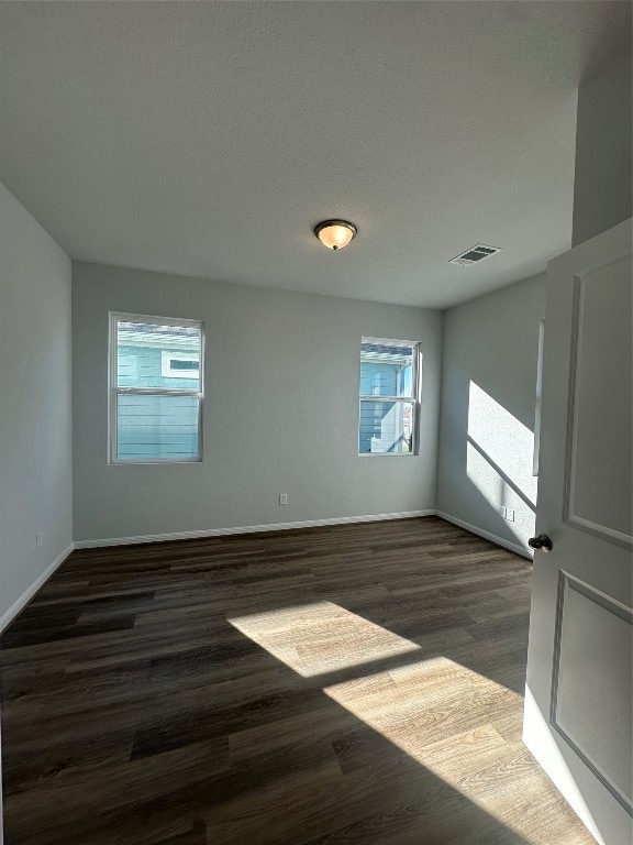 spare room with a textured ceiling and dark hardwood / wood-style floors