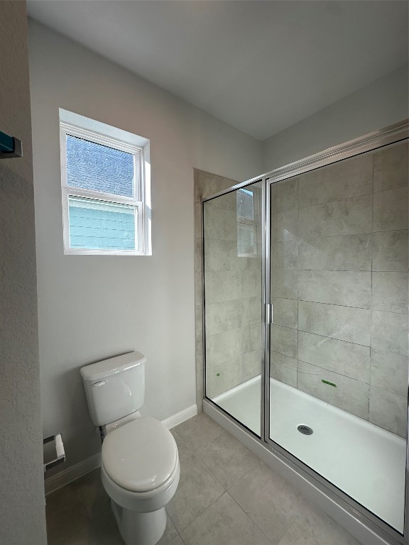 bathroom with tile patterned flooring, a shower with shower door, and toilet