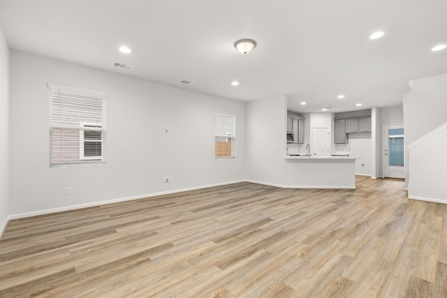 unfurnished living room with sink and light hardwood / wood-style flooring