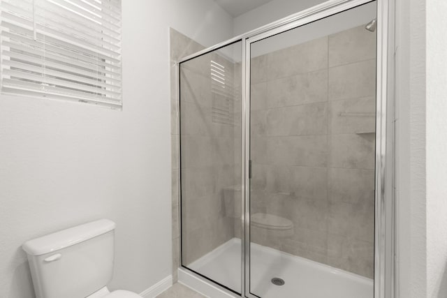 bathroom with a shower with shower door and toilet