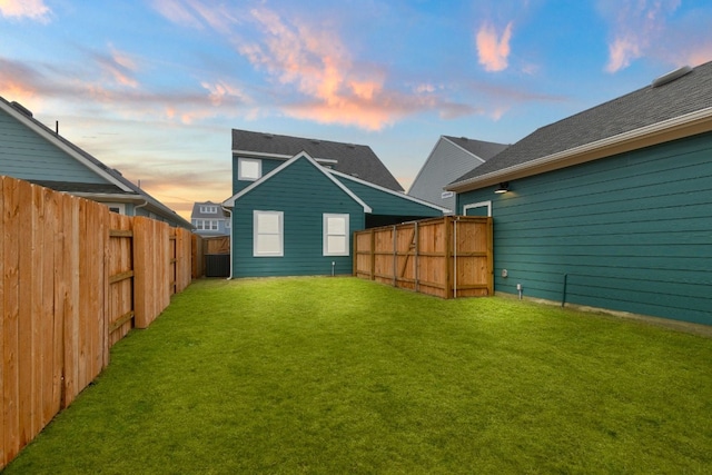 back house at dusk with a yard and central air condition unit