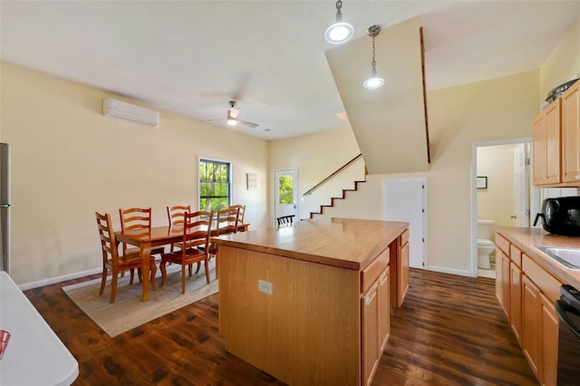 kitchen featuring a wall mounted air conditioner, a center island, dark hardwood / wood-style floors, ceiling fan, and decorative light fixtures