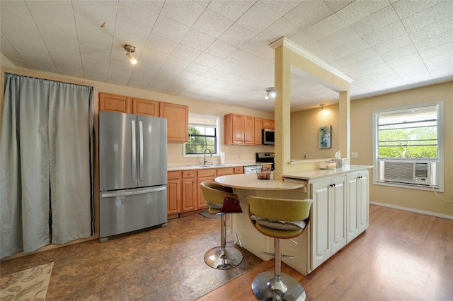 kitchen with a kitchen breakfast bar, cooling unit, sink, light hardwood / wood-style flooring, and appliances with stainless steel finishes