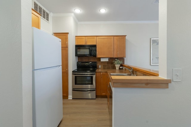 kitchen featuring backsplash, white refrigerator, sink, electric range, and kitchen peninsula