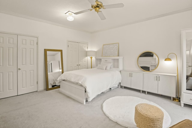 bedroom featuring light carpet, ceiling fan, multiple closets, and ornamental molding