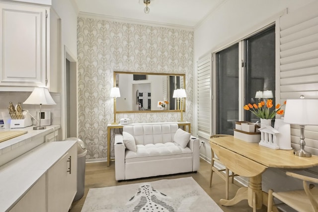 living room featuring wallpapered walls, wood finished floors, baseboards, and ornamental molding