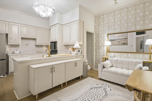 kitchen featuring black oven, wallpapered walls, freestanding refrigerator, and dark wood-style flooring