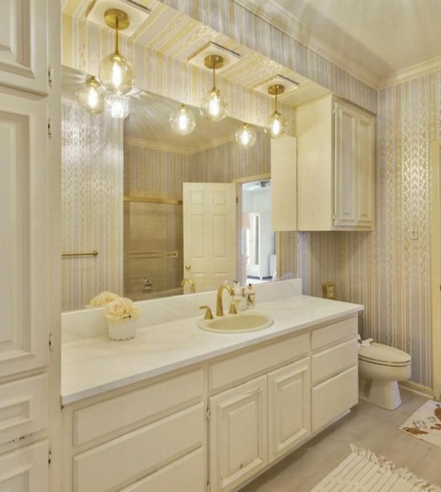 bathroom featuring toilet, crown molding, vanity, and wallpapered walls