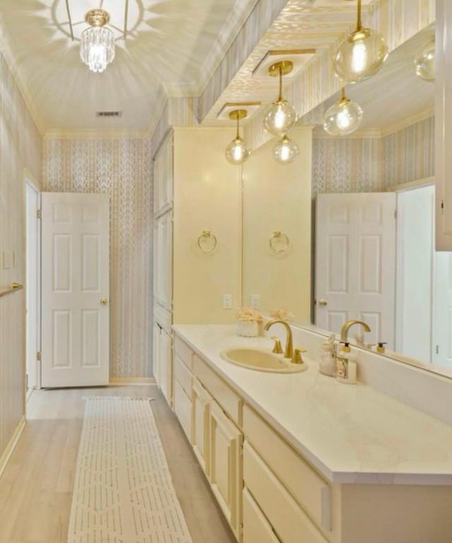 bathroom featuring baseboards, ornamental molding, vanity, and wallpapered walls