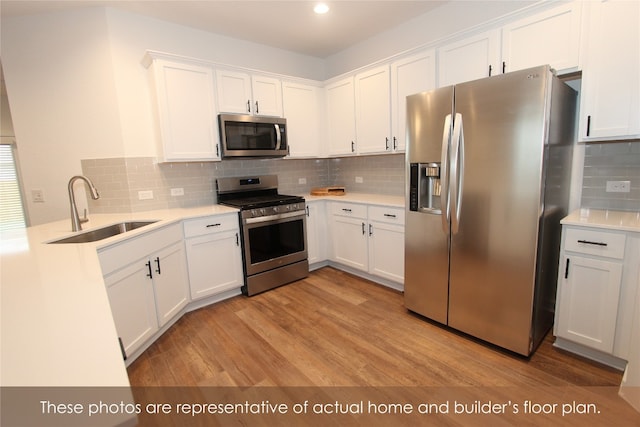 kitchen featuring backsplash, white cabinets, sink, light wood-type flooring, and appliances with stainless steel finishes