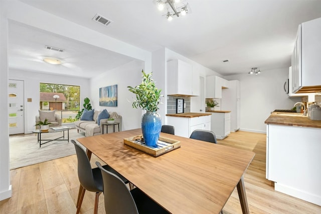 dining space with sink and light wood-type flooring