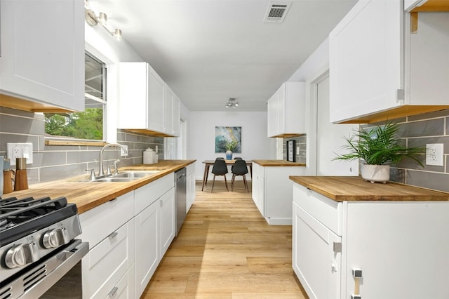 kitchen featuring white cabinets, wood counters, light hardwood / wood-style floors, and sink