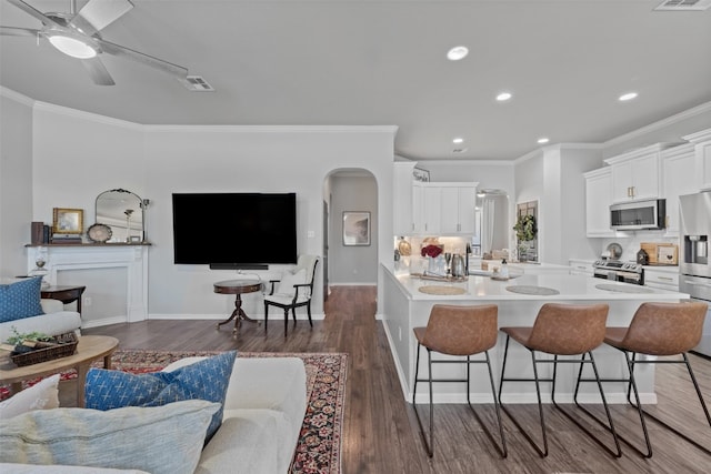 kitchen featuring white cabinetry, dark hardwood / wood-style floors, kitchen peninsula, a breakfast bar, and appliances with stainless steel finishes